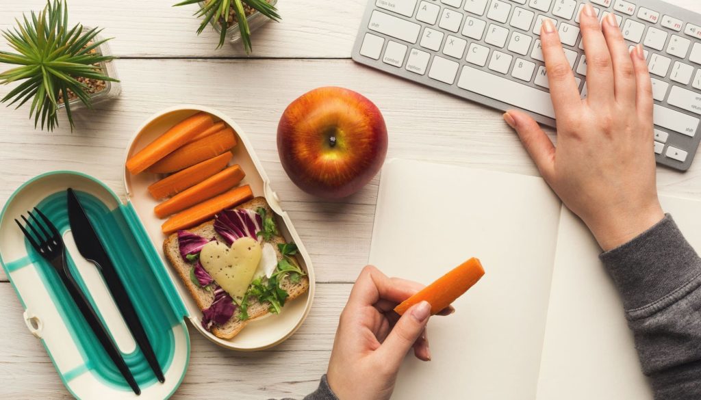 A person eating lunch while working. An example of non-productive work behaviour.
